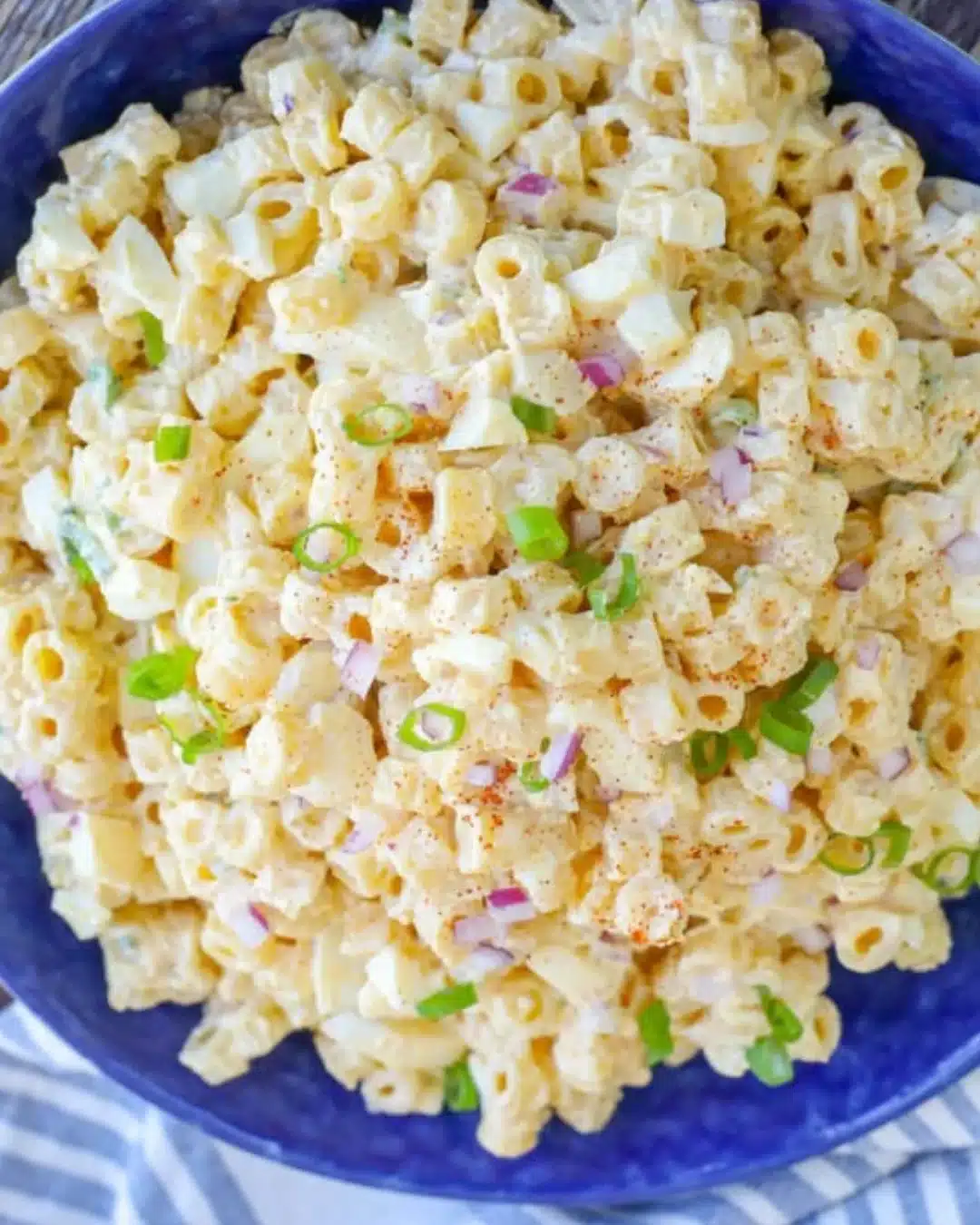 Bowl of deviled egg pasta salad garnished with parsley