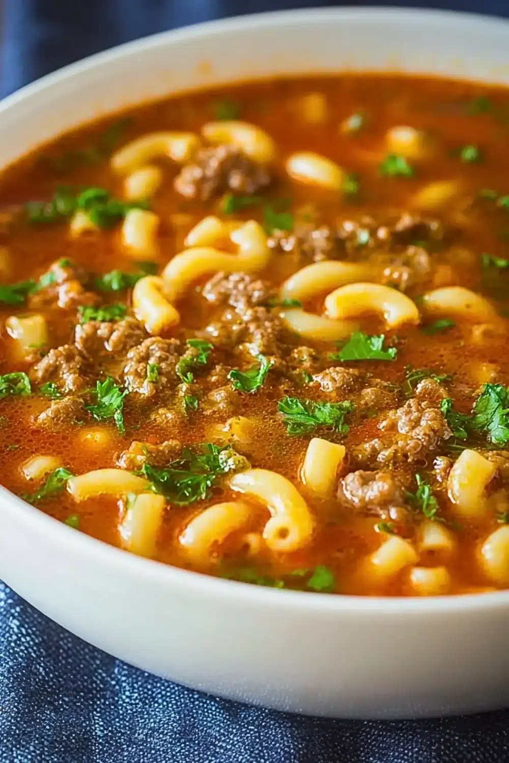 Bowl of Beef and Macaroni Soup garnished with herbs and served hot.