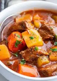 A comforting bowl of beef stew made in a crock pot with fresh vegetables.
