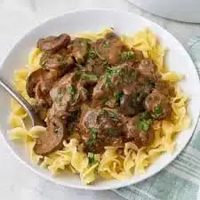 Delicious plate of Beef Stroganoff garnished with herbs and served with noodles.