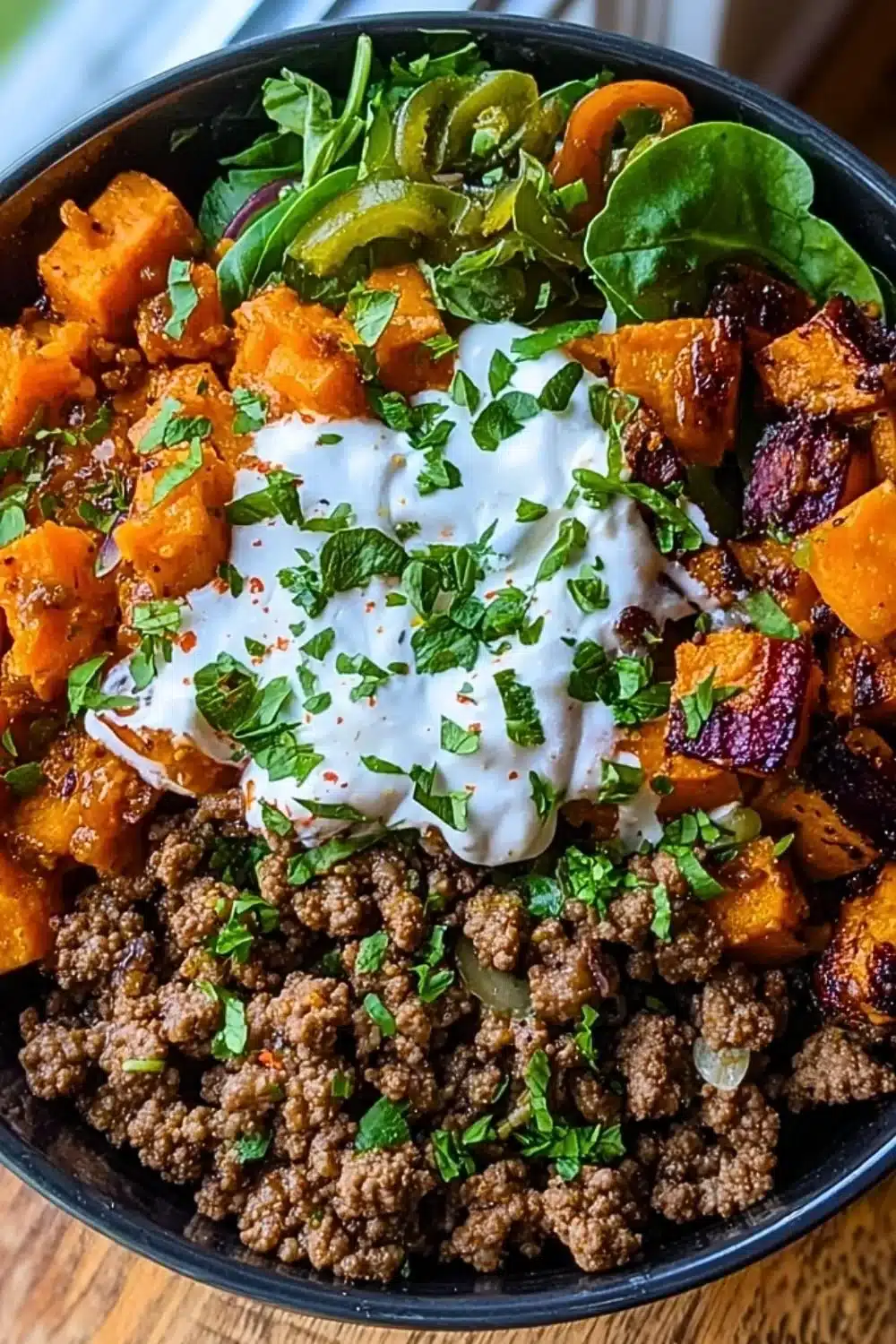 Ground Beef Sweet Potato Power Bowl topped with fresh vegetables and herbs