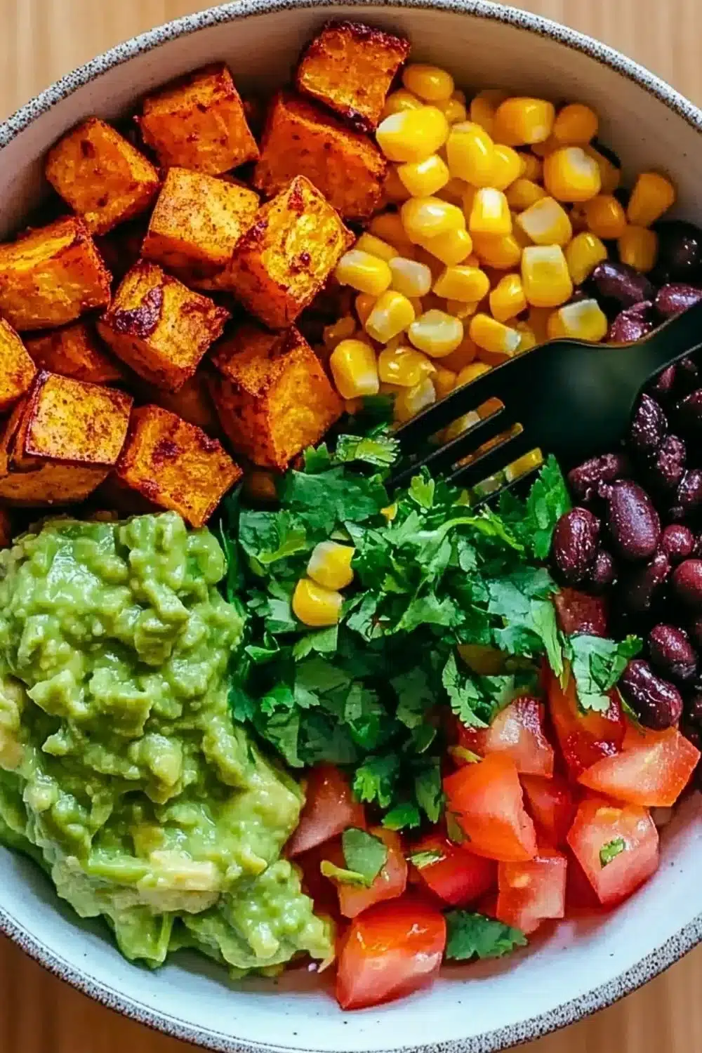 Healthy sweet potato burrito bowl topped with fresh vegetables and sauce.