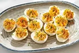 Million Dollar Bacon Deviled Eggs garnished with crispy bacon and herbs