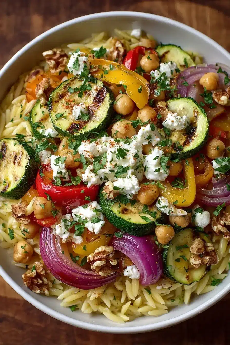Chickpea orzo bowl with feta cheese, vegetables, and dressing