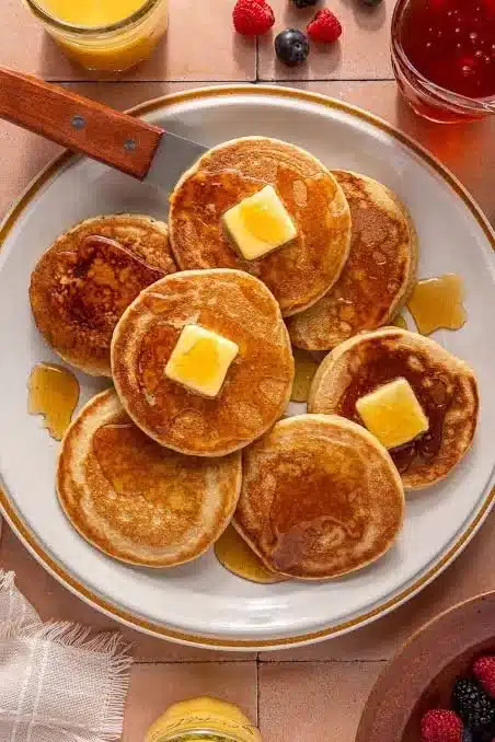 Stack of fluffy protein pancakes topped with fruits and syrup, perfect for a healthy breakfast.