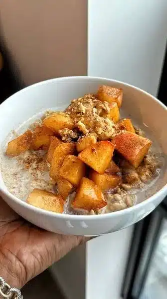 Bowl of Apple Cinnamon Protein Oatmeal topped with apple slices and cinnamon.