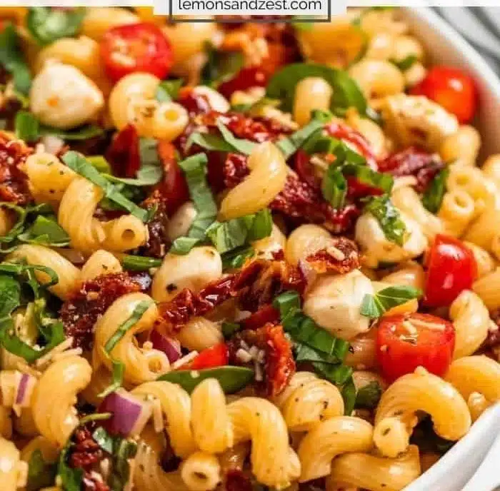 Bowl of vibrant dried tomato pasta salad with fresh vegetables and herbs