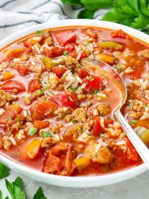 Healthy ground turkey stuffed pepper soup in a bowl topped with fresh herbs