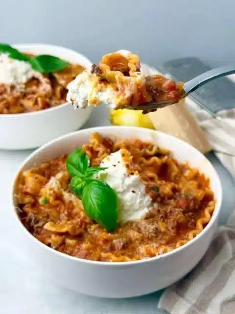 Bowl of healthy high protein lasagna soup topped with herbs and cheese.